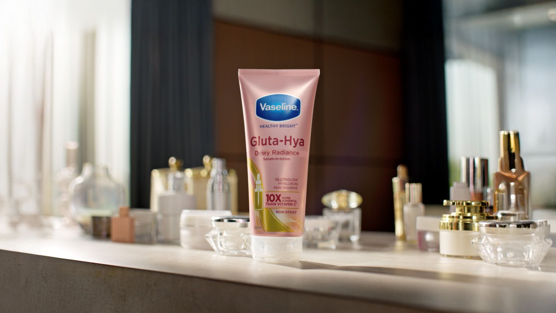 Lotion Vaseline Gluta-Hya Dewy Radiance di atas meja bersama kosmetik.