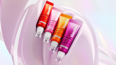 Empat varian serum bibir Vaseline Gluta Hya, Cherry Crush, Rosy Pink, Juicy Peach, dan Royal Plum, ditampilkan dengan latar belakang berwarna merah muda.