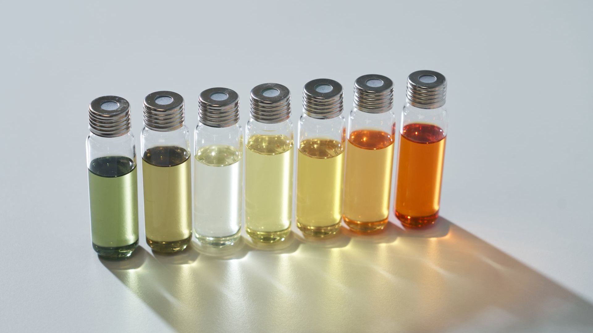 Deretan tujuh botol kaca dengan tutup perak. Berisi sampel parfum berwarna hijau, kuning, kuning keemasan, dan tidak berwarna.