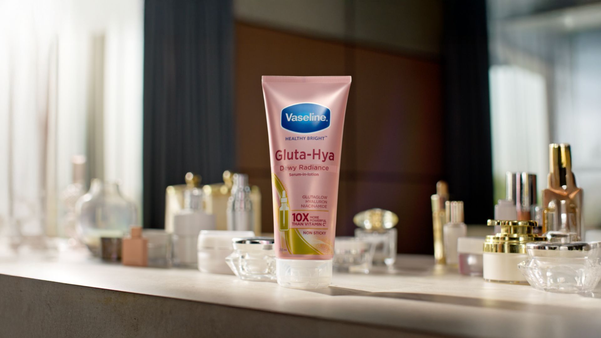 Lotion Vaseline Gluta-Hya Dewy Radiance di atas meja bersama kosmetik.
